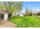 View of backyard with lush lawn, mature trees, patio with sliding door, offering an ideal outdoor space at 1213 Fairview Dr, Greenfield, IN 46140