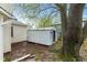 View of backyard shed with mature tree overhead, and part of home with window and gutter system at 1213 Fairview Dr, Greenfield, IN 46140