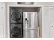 This laundry area features a modern, stacked washer and dryer plus stainless steel refrigerator at 1213 Fairview Dr, Greenfield, IN 46140