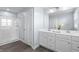 A bathroom featuring a dual sink vanity, large mirror, wood look floors, and a glass-enclosed shower at 12902 Girvan Way, Fishers, IN 46037