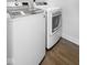 Modern laundry room featuring white front load washer and dryer on a dark wood floor at 12902 Girvan Way, Fishers, IN 46037