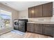 Laundry room with dark cabinets, stainless steel washer and dryer, and a large window at 1352 Trifecta Way, Westfield, IN 46074