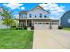 Charming two-story home with a three-car garage and well-manicured lawn on a sunny day at 13567 Moorcroft Dr, Fishers, IN 46037