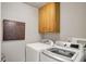 Bright laundry room featuring a modern washer and dryer set and overhead storage cabinets at 13587 Kensington Pl, Carmel, IN 46032