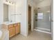 Bright bathroom with a walk-in shower, a sink with a wooden cabinet and neutral-colored tile flooring at 14323 Chariots Whisper Dr, Carmel, IN 46074