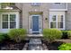 Welcoming front entrance with well-manicured bushes, blue door, and brick facade at 14323 Chariots Whisper Dr, Carmel, IN 46074