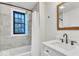 Bathroom with gray tiled shower, white vanity, modern fixtures, and a window for natural light at 15 N Campbell Ave, Indianapolis, IN 46219
