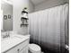 Charming bathroom featuring a white vanity, toilet, decorative shelving, and a patterned shower curtain at 238 Switchgrass Ln, New Whiteland, IN 46184