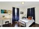 Bright bedroom with hardwood floors, blue curtains, and a decorative painting at 2404 Wildwood Ave, Anderson, IN 46011