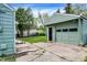 View of green garage, concrete patio, and the backyard at 2404 Wildwood Ave, Anderson, IN 46011