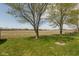 Backyard with lush green grass and trees with leaves budding, showing the surrounding open agricultural fields at 2680 Woodfield Blvd, Franklin, IN 46131