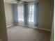 A cozy bedroom is carpeted and bright with natural light from the two large windows at 302 Sanders St, Indianapolis, IN 46225