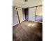 A vacant bedroom with paneled doors, stained carpet, and partially painted purple walls at 3136 Foltz St, Indianapolis, IN 46221