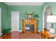Elegant fireplace with decorative accents, set against calming green walls and hardwood floors at 403 N Red Gold Dr, Trafalgar, IN 46181