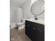 Well-maintained bathroom with a black vanity, white countertop, and modern round mirror at 4464 Four Seasons Cir, Indianapolis, IN 46226