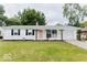 Charming single-story home featuring a white exterior, black shutters, a pink door, and a well-maintained front lawn at , Indianapolis, IN 46226