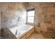 Luxurious soaking tub in main bathroom with stone surround and a window at 5624 Ottawa Pass, Carmel, IN 46033