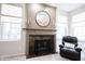Close-up of the living room fireplace, featuring a round mirror and stone surround at 5624 Ottawa Pass, Carmel, IN 46033