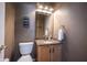 Charming powder room with granite countertop, wooden cabinets, and decorative wall art at 5624 Ottawa Pass, Carmel, IN 46033