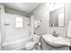 Bathroom featuring gray walls, white tiled shower and tub, white sink, and neutral colored floor tiles at 5933 Guilford Ave, Indianapolis, IN 46220