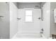Bathroom featuring gray walls, white tiled shower and tub, and natural light from the window at 5933 Guilford Ave, Indianapolis, IN 46220