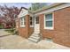 Side entrance featuring brick exterior, white trim, steps with flower pot accent, and concrete pathway at 5933 Guilford Ave, Indianapolis, IN 46220