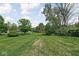 Expansive backyard featuring lush lawn, mature trees, and swing set, perfect for outdoor activities at 6223 N Parker Ave, Indianapolis, IN 46220