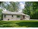 Well-maintained one-story house featuring a gravel driveway, a two-car garage, and mature landscaping at 6223 N Parker Ave, Indianapolis, IN 46220