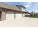 View of the three-car garage, driveway and side yard of the home surrounded by a wooden fence at 6472 Independence Ct, Pendleton, IN 46064