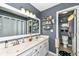 Bathroom with double sinks, large mirror, a drop in sink, and open shelving for storage at 7332 Quartz Rock Rd, Indianapolis, IN 46236