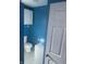 This bathroom features bright blue walls, toilet, sink, white tiled floors, and storage at 818 W 27Th St, Indianapolis, IN 46208