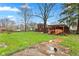 Large backyard featuring a grassy lawn, wood storage, and mature trees, ideal for outdoor recreation and relaxation at 874 S Sycamore Dr, Greenfield, IN 46140