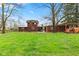 Expansive backyard with lush green grass, trees, patio, and covered wood storage perfect for outdoor activities at 874 S Sycamore Dr, Greenfield, IN 46140