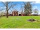 Spacious backyard with grassy lawn, trees, fire pit and wood storage, ideal for outdoor enjoyment at 874 S Sycamore Dr, Greenfield, IN 46140