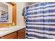 Bathroom with a wood framed mirror, bright lighting, and a blue-striped shower curtain, offering a spa-like retreat at 874 S Sycamore Dr, Greenfield, IN 46140