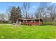 Lovely single-story home with a cozy front porch adorned with the American flag and lush, green landscaping at 874 S Sycamore Dr, Greenfield, IN 46140