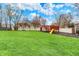 Spacious backyard featuring a well-maintained lawn and a red playset with a slide and swings for outdoor fun at 9319 Oak Knoll Ln, Fishers, IN 46037