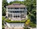 Multi-level waterfront home with multiple balconies and outdoor seating area surrounded by mature trees at 10919 Brigantine Dr, Indianapolis, IN 46256