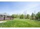 Expansive backyard view with a deck, lush green grass, and a paved walking path surrounded by trees at 11327 Guy St, Fishers, IN 46038