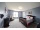 Cozy bedroom with blue walls, soft carpeting, a wooden-frame bed, and a comfortable recliner chair by the window at 11327 Guy St, Fishers, IN 46038