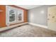 Neutral bedroom featuring carpet, grey and orange walls, and bright natural light from two windows at 122 S 3Rd Ave, Beech Grove, IN 46107