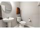 Powder room features a pedestal sink, toilet, round mirror, and shelving at 1242 Petit Verdot Dr, Westfield, IN 46074