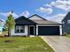 Beautifully landscaped one-story home featuring black trim, siding, and a two-car garage at 1319 Fleming Dr, Greenfield, IN 46140