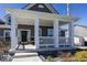 Inviting front porch with white columns, a black front door, and a cozy seating area, adding curb appeal at 13705 Beam Ridge Dr, McCordsville, IN 46055