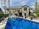 Backyard pool with brick house in the background, surrounded by green lawn, potted plants, and lounge seating at 13705 Beam Ridge Dr, McCordsville, IN 46055