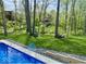 Backyard pool with basketball hoop, beautiful lawn, and wooded areas in background of this property at 13705 Beam Ridge Dr, McCordsville, IN 46055