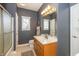 Well-lit bathroom with blue walls, shower and tub, sink and vanity, and a large framed mirror at 14491 Jeremy Dr, Carmel, IN 46033