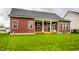 A beautiful, green lawn behind a red house with a covered porch supported by elegant white pillars and with a ceiling fan at 15144 Bentfield Ct, Fishers, IN 46037