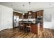 Well-lit kitchen features stainless steel appliances, dark wood cabinets, hardwood floors, and an island with barstool seating at 15144 Bentfield Ct, Fishers, IN 46037