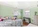 A bedroom with mint green walls features hardwood floors, two windows, and a whimsical array of pillows at 1850 Cruft St, Indianapolis, IN 46203